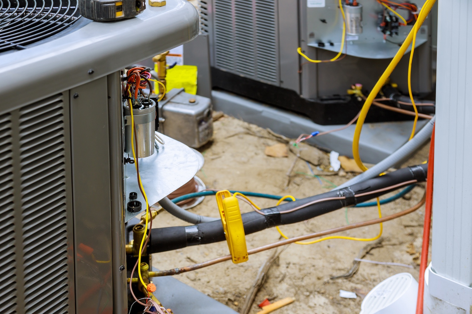 HVAC system installation with exposed wires and cables in an outdoor setting.